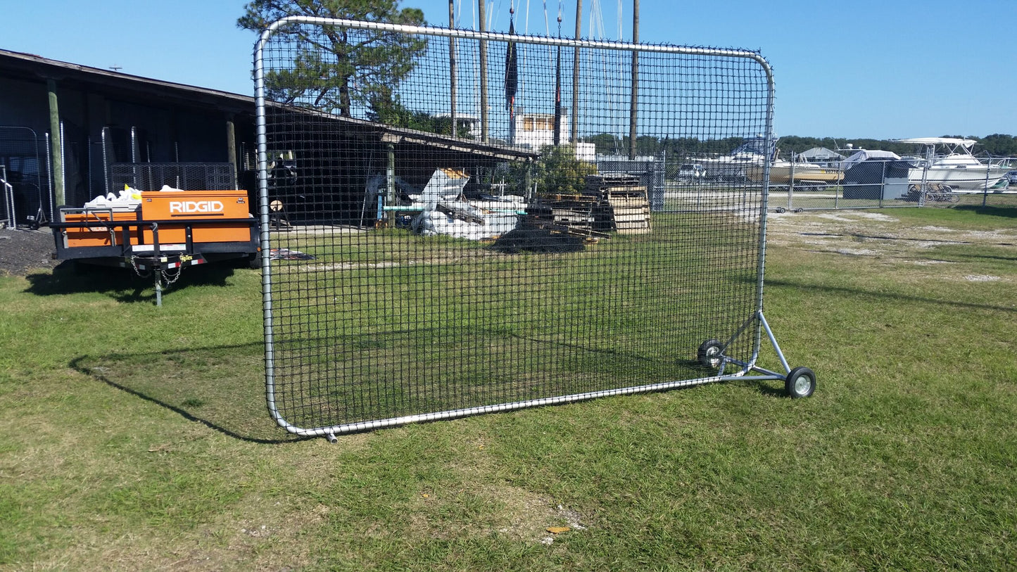 A baseball field with a large net on the grass.