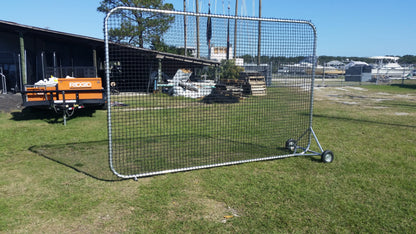 A baseball field with a large net on the grass.