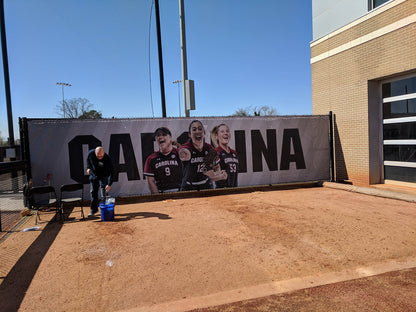 A person sitting on the ground next to a large sign.